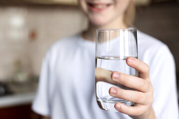 The girl holds a glass of clean water in her hand. The hand reaches forward. The concept of...