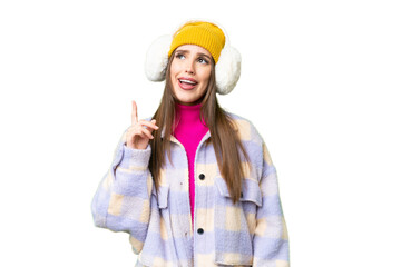 Young woman wearing winter muffs over isolated chroma key background pointing up and surprised