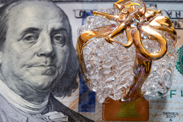 Glass present box with golden ribbon on 100 dollar banknote