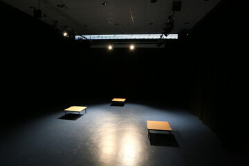 modern drama performance drama studio, completely blacked out with spotlights on perfroming space