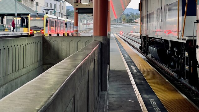 LOS ANGELES, CA, DEC 2022: wide view from low angle along the side of a Metrolink train beside empty platform at Union Station in Downtown. LA Metro Gold Line train visible in background