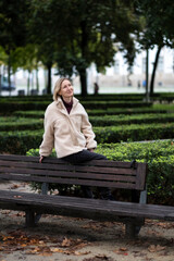 A woman sits on the back of a park bench.