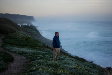 Obraz premium A man stands on the oceanfront against the backdrop of the morning surf.