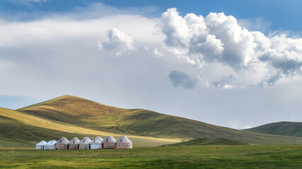 Traditional Yurt tent camp at the Song Kul lake plateau in Kyrgyzstan. Yurt tents are traditional, portable tents made of felt that are used as a form of accommodation in the country. - obrazy, fototapety, plakaty