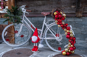 Fototapeta na wymiar Bicycle with Christmas decoration. One white bicycle with golden and red Christmas balls.