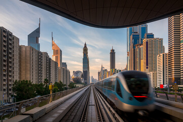 Dubai metro train entering the station with background of high rise building in Dubai downtown.