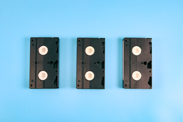 Three retro videotapes lie in the middle on a blue.