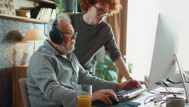 Old man and his grandson get annoyed and stressed playing games on the computer