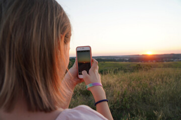 girl photographing the sunset on a smartphone