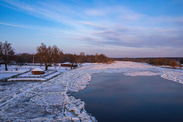 Frozen harbor and river covered with ice and floes in winter sunny sunset. Winter.
