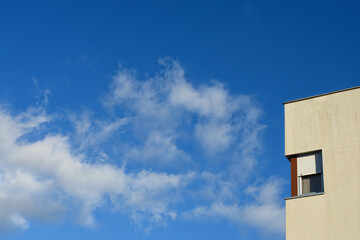 Clouds in the blue sky with a building with a window next to it