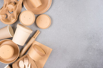 Various paper utensils around over gray concrete background with copy space. Eco tableware, sustainable food packaging concept