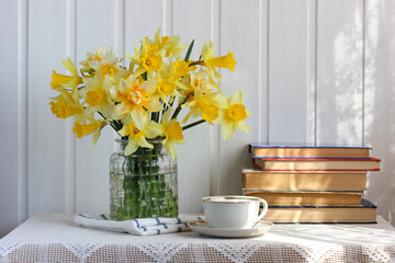 still life with a bouquet of daffodils and old books.
