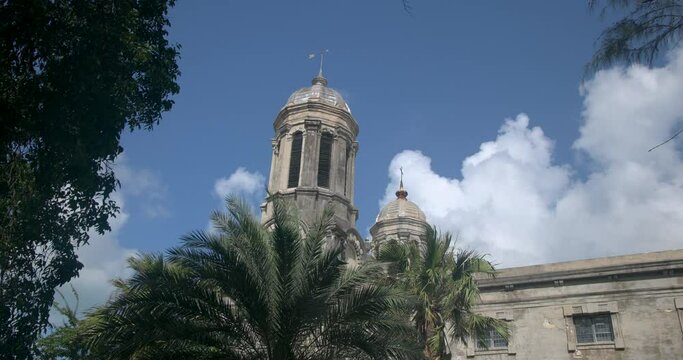 Antigua Caribbean palm trees clouds St Johns Cathedral clock tower. Church of Diocese North Eastern Caribbean and Aruba. Anglican Church of England. Originally built 1683. Seventy foot twin towers.