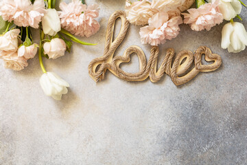 Valentine's Day greeting card with "love" letters and beautiful spring flowers on light gray background. Valentine's day, Womans day, mothers day concept. View from above. Copy space.