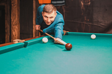 Fototapeta premium Playing billiards, a man as an amateur plays billiards, a sports board game.