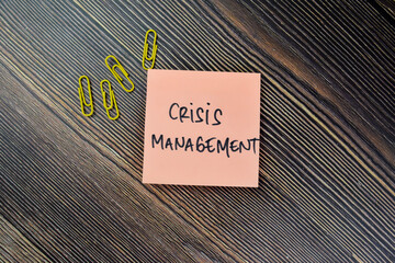 Concept of Crisis Management write on sticky notes isolated on Wooden Table.