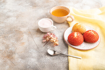 French custard dessert shu cake and cup of green tea on brown concrete, side view, copy space.