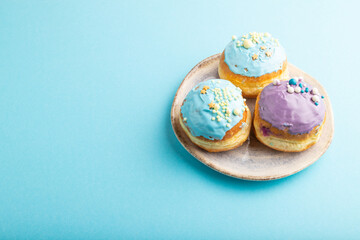 Purple and blue glazed donut on blue pastel, side view, copy space.