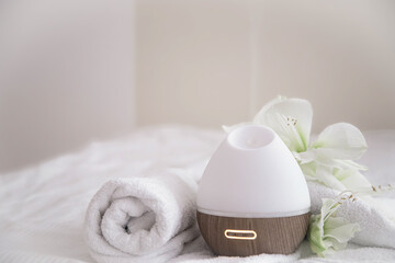 Spa composition with aroma diffuser and towel on a blurred background.