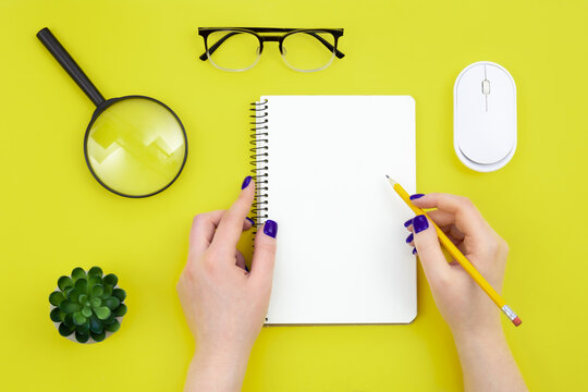 Blank notepad in female hands on a green background, flat lay.