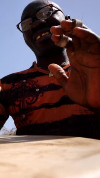 Vertical video of Medium shot of black man playing djembe with plaster on finger