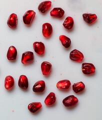 Ripe red pomegranate seeds on a white background.