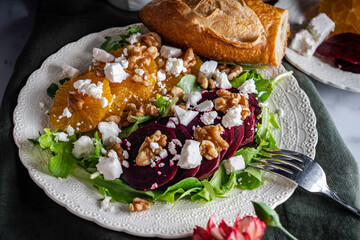 Fototapeta na wymiar Beet salad with oranges, feta cheese, and toasted walnuts on a bed of mixed greens.
