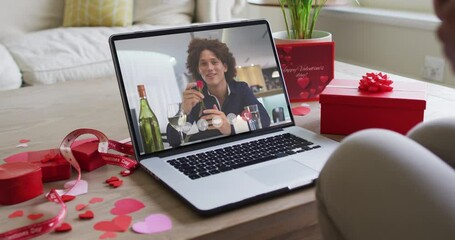 Happy biracial man with wine making valentine's day video call on laptop