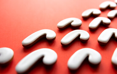A lot of gingerbread candy cane shaped cookies on a red background.