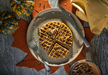 Overhead photo of a paleo pumpkin waffle with orange autumn table setting. - 557776085
