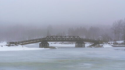 A rail bridge walking trail, during a foggy winter warming in Madawaska Community Park, South Algonquin, Ontario