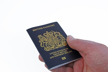 An UK Passport being held in hand  isolated on a white background.