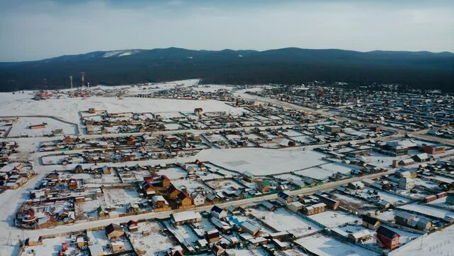 Flying over the houses of the huzhir village on Olkhon, the shore of Lake Baikal. Baikal, Siberia, Russia. A winter Siberian countryside landscape. Drone aerial shot