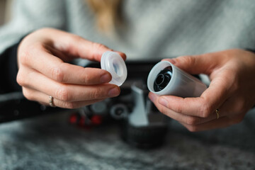 Girl's hands prepare an analog camera. Experienced photographer opens the container of a roll of...
