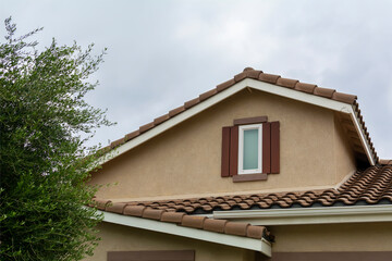 Suburban house attic window with cloudy sky background, Menifee, California, USA
