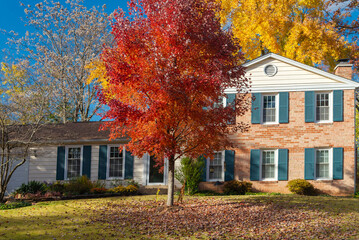 Fototapeta na wymiar Beautiful autumn exterior of the house at sunset. Yard with green grass and autumn leaves.