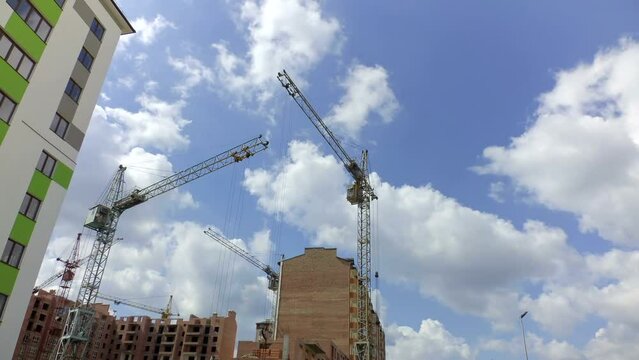 Construction cranes over houses. Timelapse. Construction
