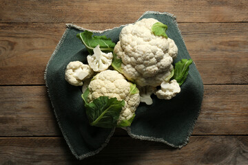 Cut and whole cauliflowers on wooden table, top view