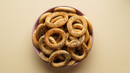 Bowl with delicious ring shaped Sushki (dry bagels) on beige background, top view