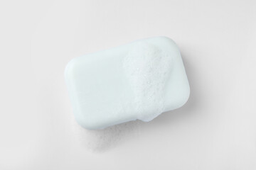 Soap with fluffy foam on white background, top view