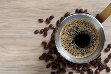 Hot turkish coffee pot and beans on wooden table, flat lay. Space for text