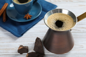 Hot turkish coffee pot and chocolate on white wooden table, space for text