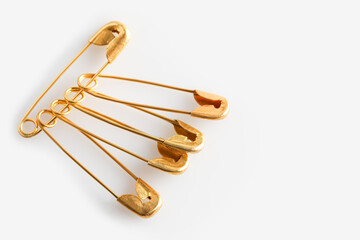 Golden safety pins on white background, closeup. Space for text