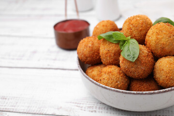 Bowl of delicious fried tofu balls with basil on white wooden table, closeup. Space for text