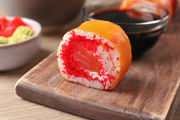 Delicious sushi roll with salmon and tobiko on wooden table, closeup