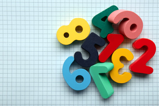 Colorful numbers on sheet of grid paper, flat lay