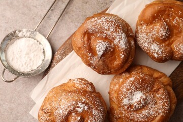 Delicious profiteroles with powdered sugar on grey table, flat lay