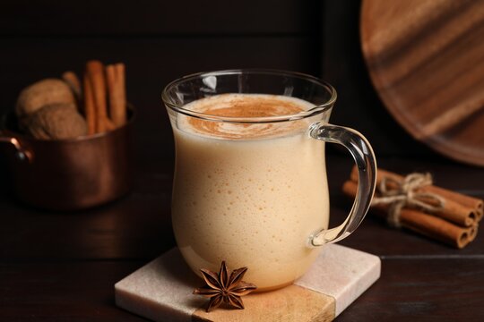 Delicious eggnog with spices on wooden table
