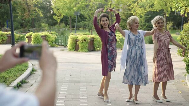 Senior Chinese friends taking pictures in park,4K